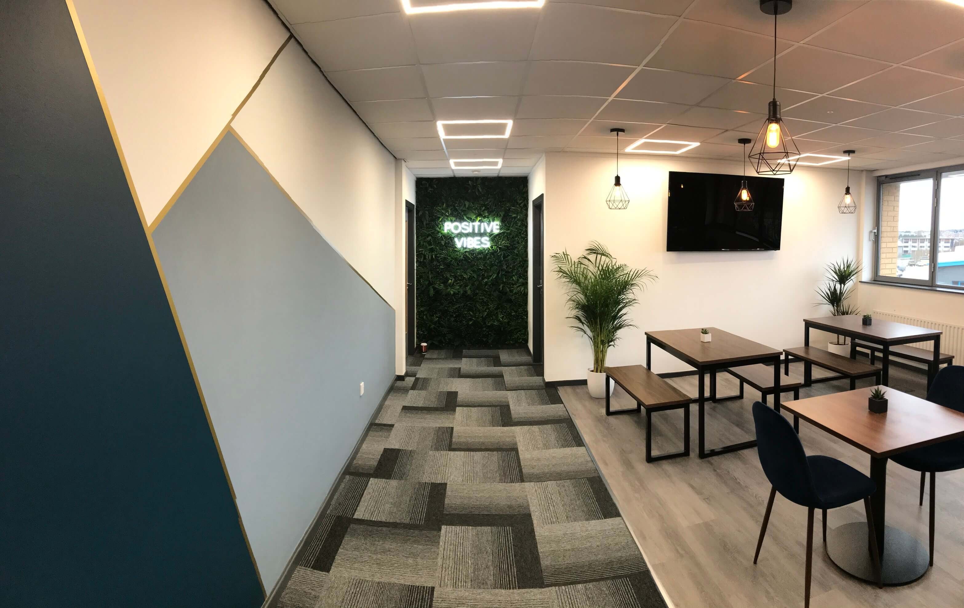 A bright Hope Park breakout area with a 'Positive Vibes' neon sign, plants, and modern seating